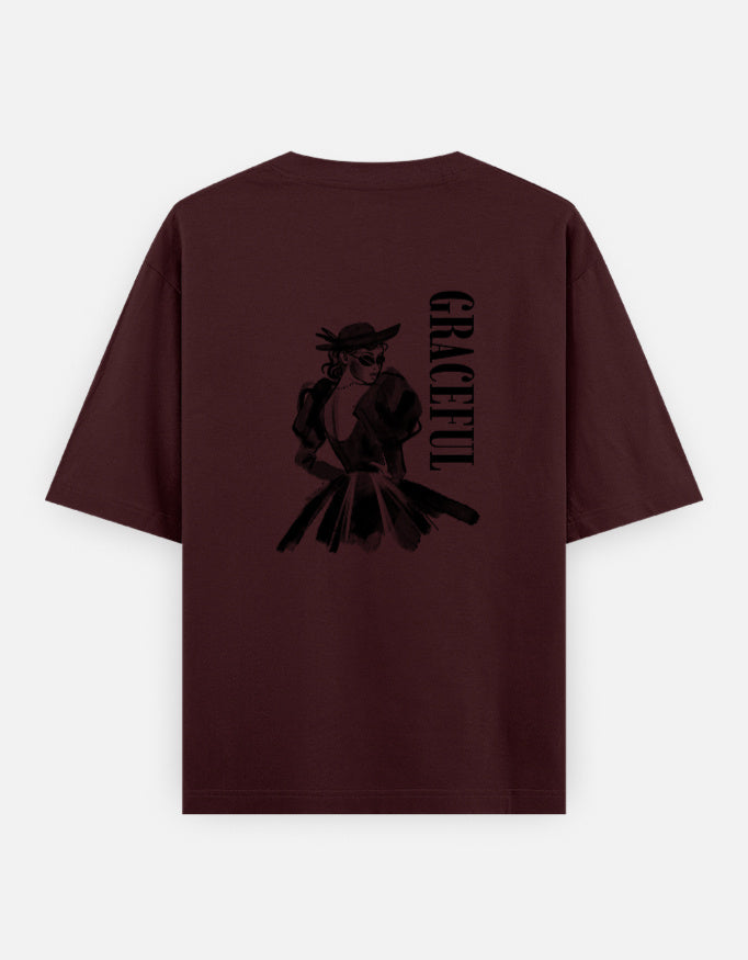 Maroon oversized unisex t shirt featuring a back print of a monochrome fashion illustration of a stylish woman wearing a hat and dress alongside vertical GRACEFUL typography. Made from premium 240 GSM 100% cotton with a relaxed oversized fit. Available in Black and Cream by Shisha.