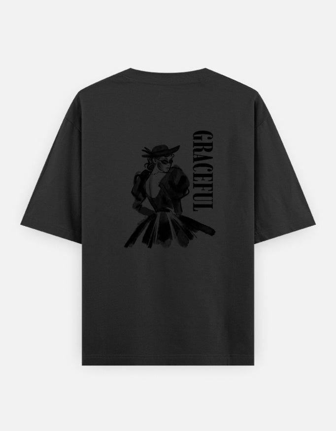 Black oversized unisex t shirt featuring a back print of a monochrome fashion illustration of a stylish woman wearing a hat and dress alongside vertical GRACEFUL typography. Made from premium 240 GSM 100% cotton with a relaxed oversized fit. Available in Black and Cream by Shisha.