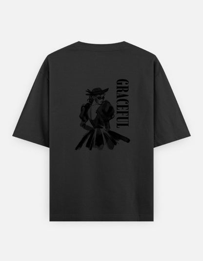 Black oversized unisex t shirt featuring a back print of a monochrome fashion illustration of a stylish woman wearing a hat and dress alongside vertical GRACEFUL typography. Made from premium 240 GSM 100% cotton with a relaxed oversized fit. Available in Black and Cream by Shisha.