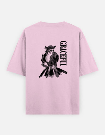 Pink oversized unisex t shirt featuring a back print of a monochrome fashion illustration of a stylish woman wearing a hat and dress alongside vertical GRACEFUL typography. Made from premium 240 GSM 100% cotton with a relaxed oversized fit. Available in Black and Cream by Shisha.