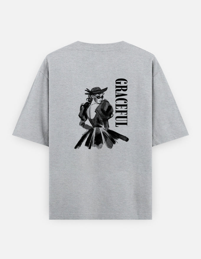 Grey oversized unisex t shirt featuring a back print of a monochrome fashion illustration of a stylish woman wearing a hat and dress alongside vertical GRACEFUL typography. Made from premium 240 GSM 100% cotton with a relaxed oversized fit. Available in Black and Cream by Shisha. 