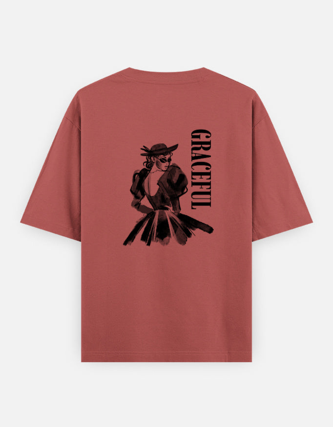 Coral oversized unisex t shirt featuring a back print of a monochrome fashion illustration of a stylish woman wearing a hat and dress alongside vertical GRACEFUL typography. Made from premium 240 GSM 100% cotton with a relaxed oversized fit. Available in Black and Cream by Shisha.