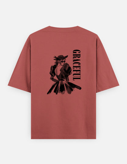 Coral oversized unisex t shirt featuring a back print of a monochrome fashion illustration of a stylish woman wearing a hat and dress alongside vertical GRACEFUL typography. Made from premium 240 GSM 100% cotton with a relaxed oversized fit. Available in Black and Cream by Shisha.