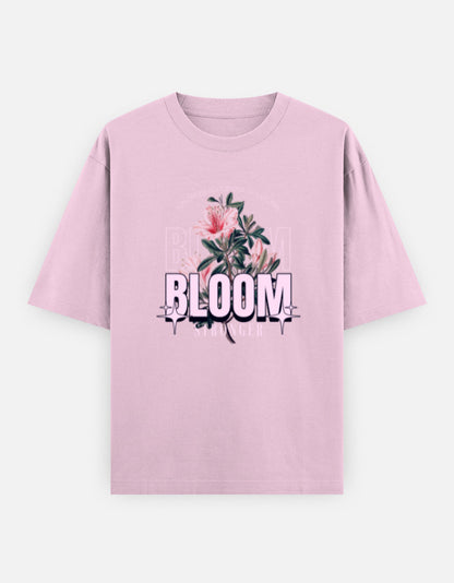 Pink oversized unisex t shirt featuring a front print with the word BLOOM in bold pastel typography layered with delicate pink flowers and botanical artwork. Made from premium 240 GSM 100% cotton with a relaxed oversized fit. Available in Black and Cream by Shisha.