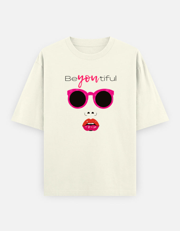Off-White oversized unisex t shirt featuring a front print of a minimalist fashion face with bright pink sunglasses, bold pink lips, and the word Beyoutiful above.