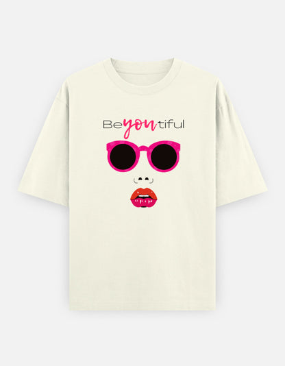 Off-White oversized unisex t shirt featuring a front print of a minimalist fashion face with bright pink sunglasses, bold pink lips, and the word Beyoutiful above.