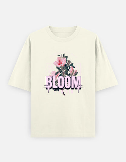 Off-White oversized unisex t shirt featuring a front print with the word BLOOM in bold pastel typography layered with delicate pink flowers and botanical artwork. Made from premium 240 GSM 100% cotton with a relaxed oversized fit. Available in Black and Cream by Shisha.